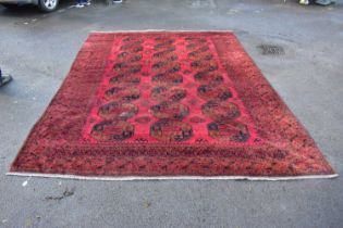 A large Eastern style red ground rug with elephant foot symbols. 365x280cm