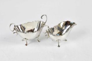 An Edward VII hallmarked silver cream jug and twin handled sugar bowl, each with cast scrolling