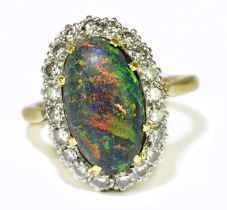 A yellow metal black opal and diamond set ring, the domed opal set within a border of twenty round