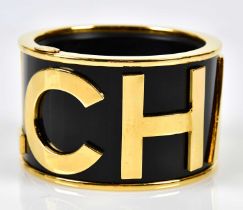 CHANEL; a broad flat sectioned bangle, circa 1986-1989, with gold plated raised Chanel lettering and