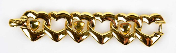 YVES SAINT LAURENT; a gold tone metal heart bracelet, stamped 'YSL', with large glass bead