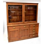 A mid-20th century pitch pine side cabinet, the upper section with pair of glazed doors above a base