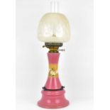 A late 19th/early 20th century oil lamp with pink glazed pottery column and base, with central