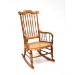 A late 19th early 20th century country-style light oak rocking chair with twist cane back and sides,