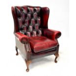 A modern oxblood red leather button wing back armchair.Condition Report: Overall solid but used