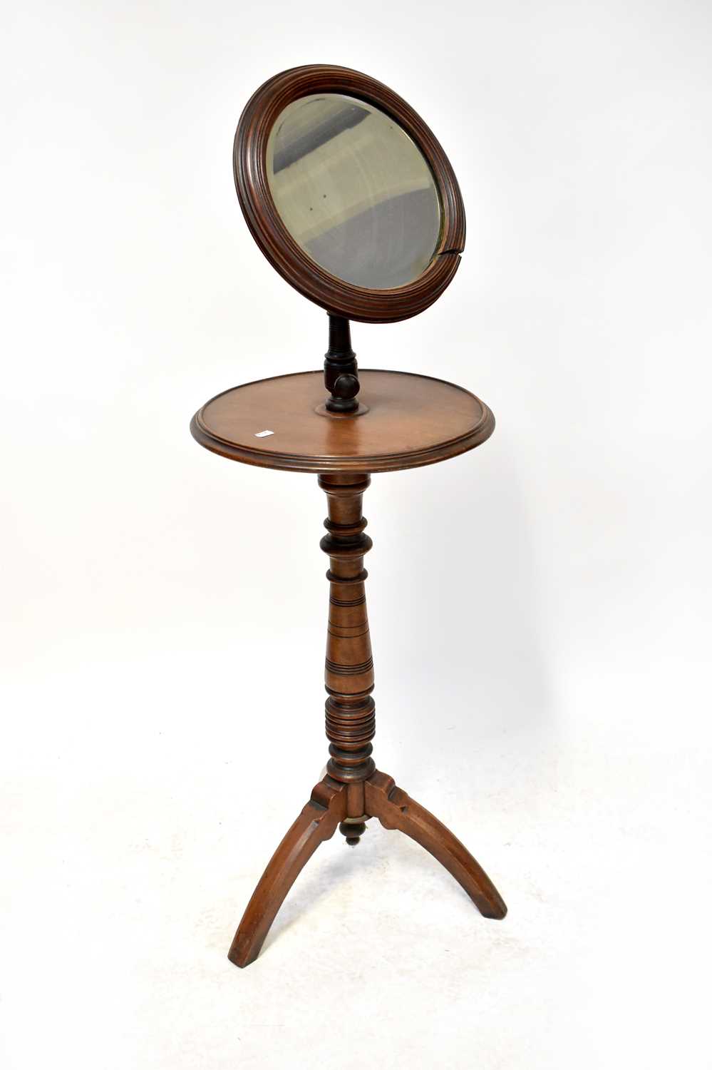 An Edwardian mahogany vanity stand with circular bevel edge mirror on an adjustable arm, with