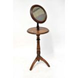 An Edwardian mahogany vanity stand with circular bevel edge mirror on an adjustable arm, with