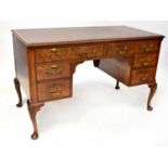 A 20th century reproduction walnut and mahogany kneehole desk with three-section leather inset