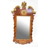 A 19th century walnut framed mirror with scalloped edge surmounted by a gilt painted bird, with