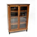 An early 20th century oak twin glazed door bookcase with three interior shelves, to plinth and block