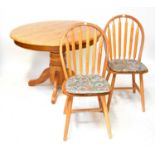 A contemporary oak circular table with robust turned column and four outswept supports, diameter