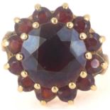 A 9ct gold garnet cluster ring, the large central garnet surrounded by smaller red stones in caged