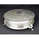 A George V hallmarked silver circular box with engine turned lid, cylindrical body, raised on