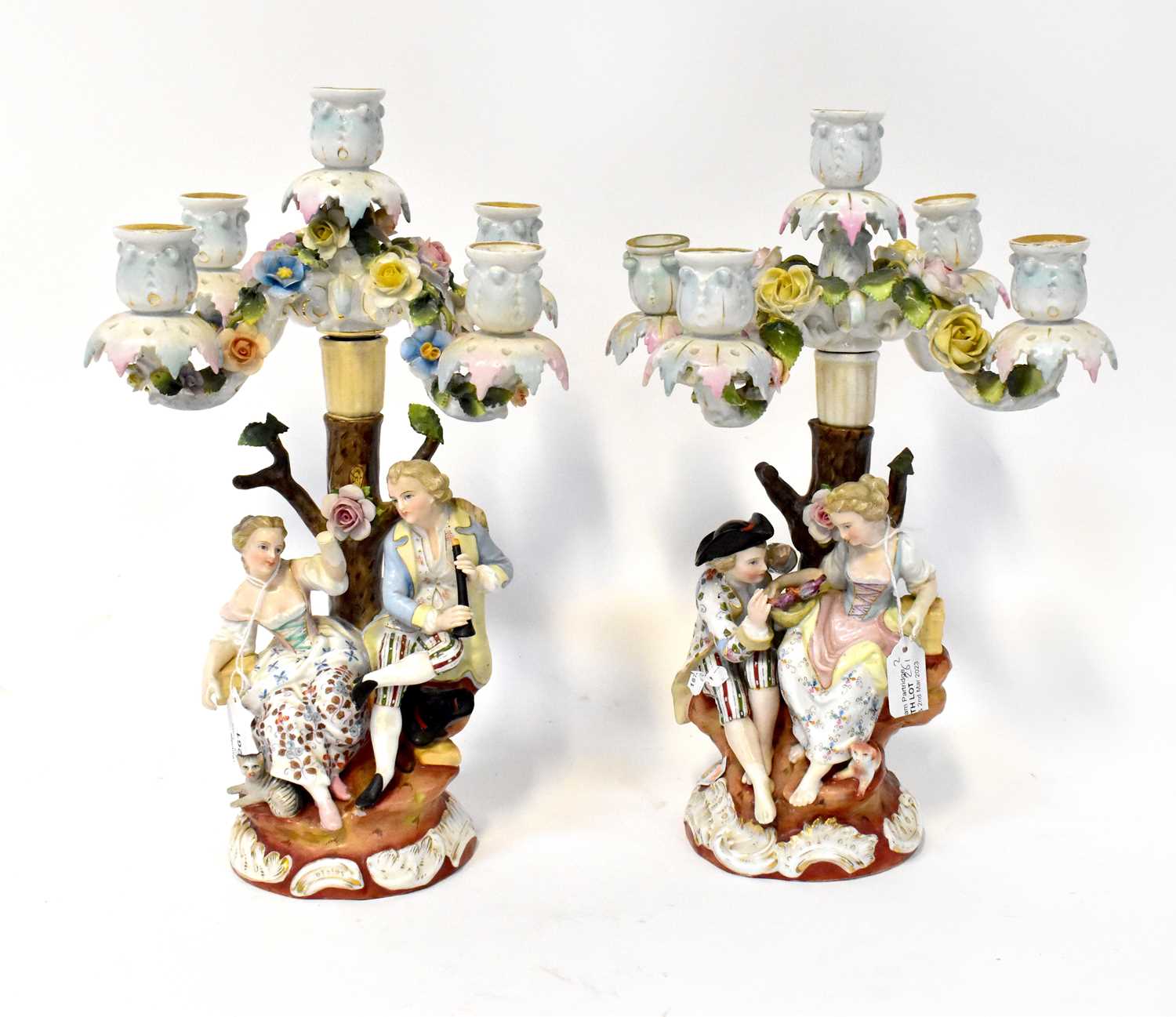 SITZENDORF; a pair of four branch figures candlesticks, with courting couples under rose strewn