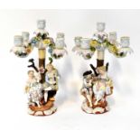 SITZENDORF; a pair of four branch figures candlesticks, with courting couples under rose strewn