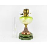 A 19th century oil lamp with green glass font, raised on copper tapered stem with acanthus leaf