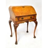 An early 20th century walnut veneered drop-front bureau with curved shaped top, leather inset fall