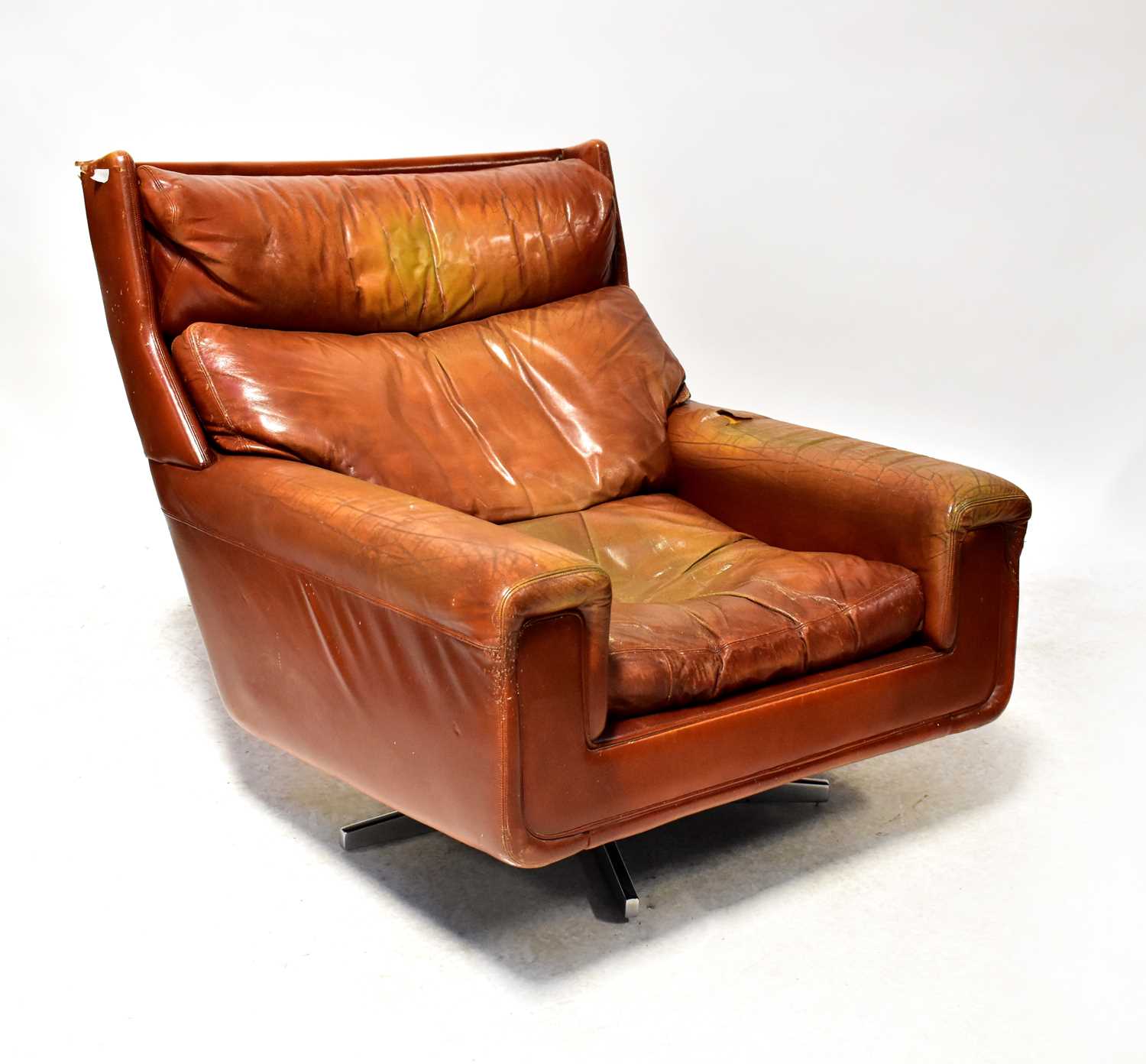 A retro oversized tan leather lounge chair raised on four outswept alloy supports (af).