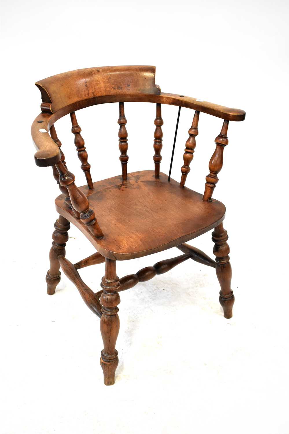 An early 20th century oak captain's chair with turned bobbin seat supports and curved back rails