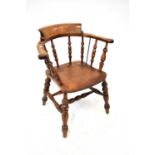 An early 20th century oak captain's chair with turned bobbin seat supports and curved back rails