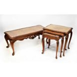 A reproduction burr walnut nest of three shaped tables with inset glass tops, raised on carved