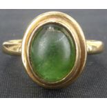 A 9ct gold emerald ring, the half emerald cabochon of oval form, in a bezel set lipped mount, on