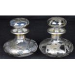 Two Art Nouveau silver and glass perfume decanters of squat form, the stopper and body decorated