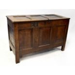 A 18th and later century oak coffer with panel top and front, raised on stile feet, carved