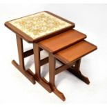 A retro dark stained teak nest of three tables, the largest set with four floral tiles, 45 x 49 x