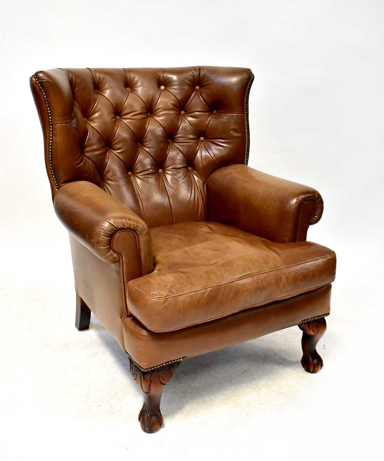 A mid-20th century conker brown leather Chesterfield wing back chair to cabriole supports.