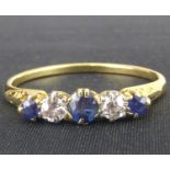 A 9ct gold diamond and sapphire ring, the central claw set sapphire flanked by two small diamonds,