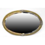 An oval brass framed mirror with applied flower and leaf decoration with bevelled glass plate,