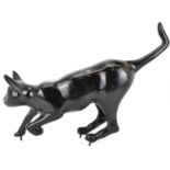 A vintage cast iron model of a cat ready to leap, painted black with painted green eyes and three