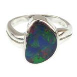 A contemporary 14ct white gold ring with bezel set opal shard, showing blues, greens and reds,