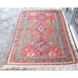 A late 19th/early 20th century Middle Eastern wool rug with geometric patterns on a red ground,