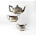 A George V hallmarked silver three-piece tea service of oval form, the teapot with ebonised wooden