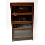 An early 20th century oak four-section stackable bookcase with four lift-up and over glazed doors.