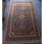 A Middle Eastern rug with geometric cascading pattern in a floral border, on a red ground, 212 x