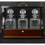 A 20th century mahogany cased three-decanter tantalus, the matching three square English hand made