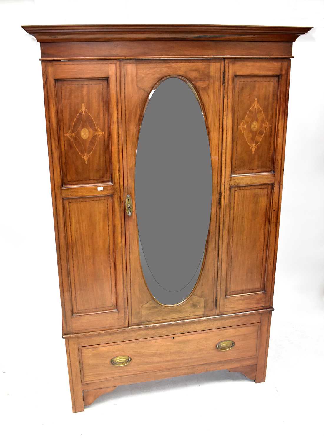 An Edwardian inlaid mahogany wardrobe, the stepped pediment above oval bevel edge mirrored door