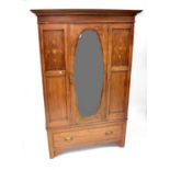 An Edwardian inlaid mahogany wardrobe, the stepped pediment above oval bevel edge mirrored door