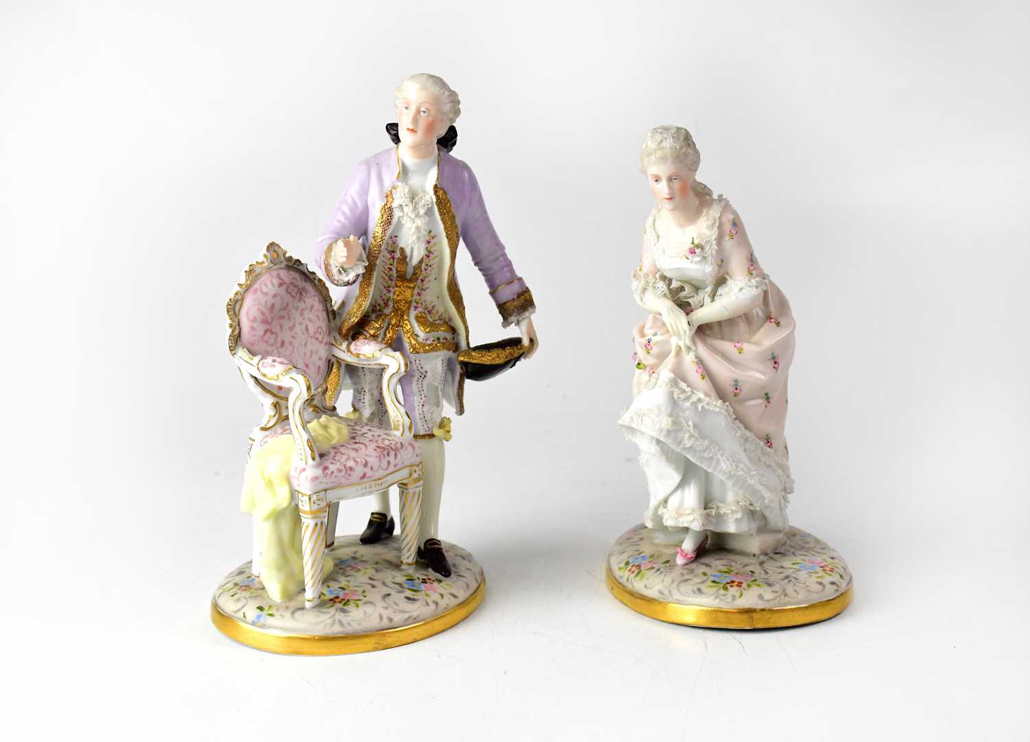 SITZENDORF; a pair of late 19th/early 20th century figures in period costume, both to oval floral