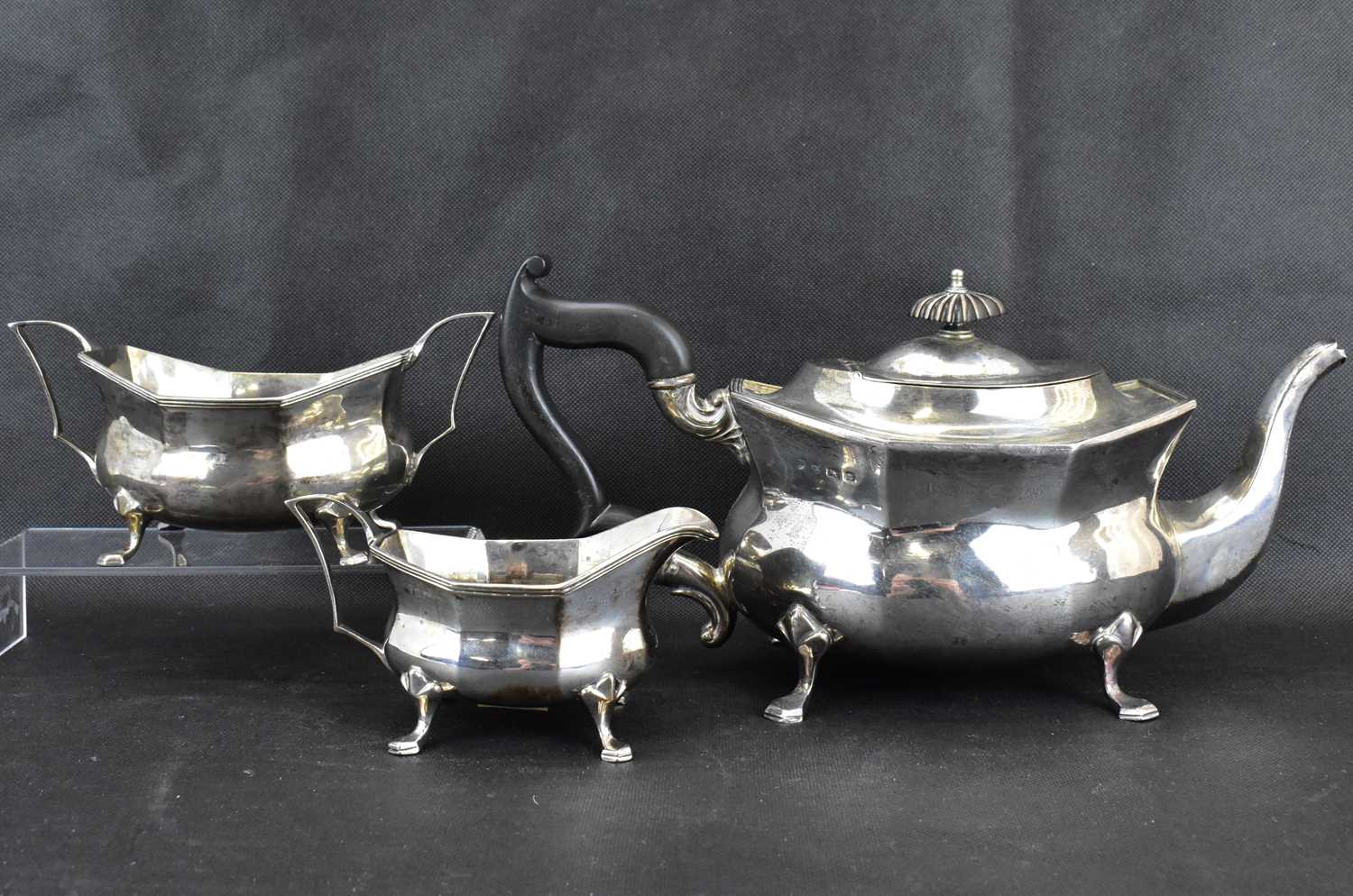 A George V hallmarked silver three-piece tea service with ebonised handle and knop, raised on four