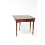 An early 20th century mahogany fold-over tea table raised on turned tapering supports to brass