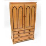 A pine linen press converted to a wardrobe, the upper section with four arched panels above a base