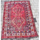 A vintage Turkish-style rug with two central medallions in three floral borders, on a red ground,