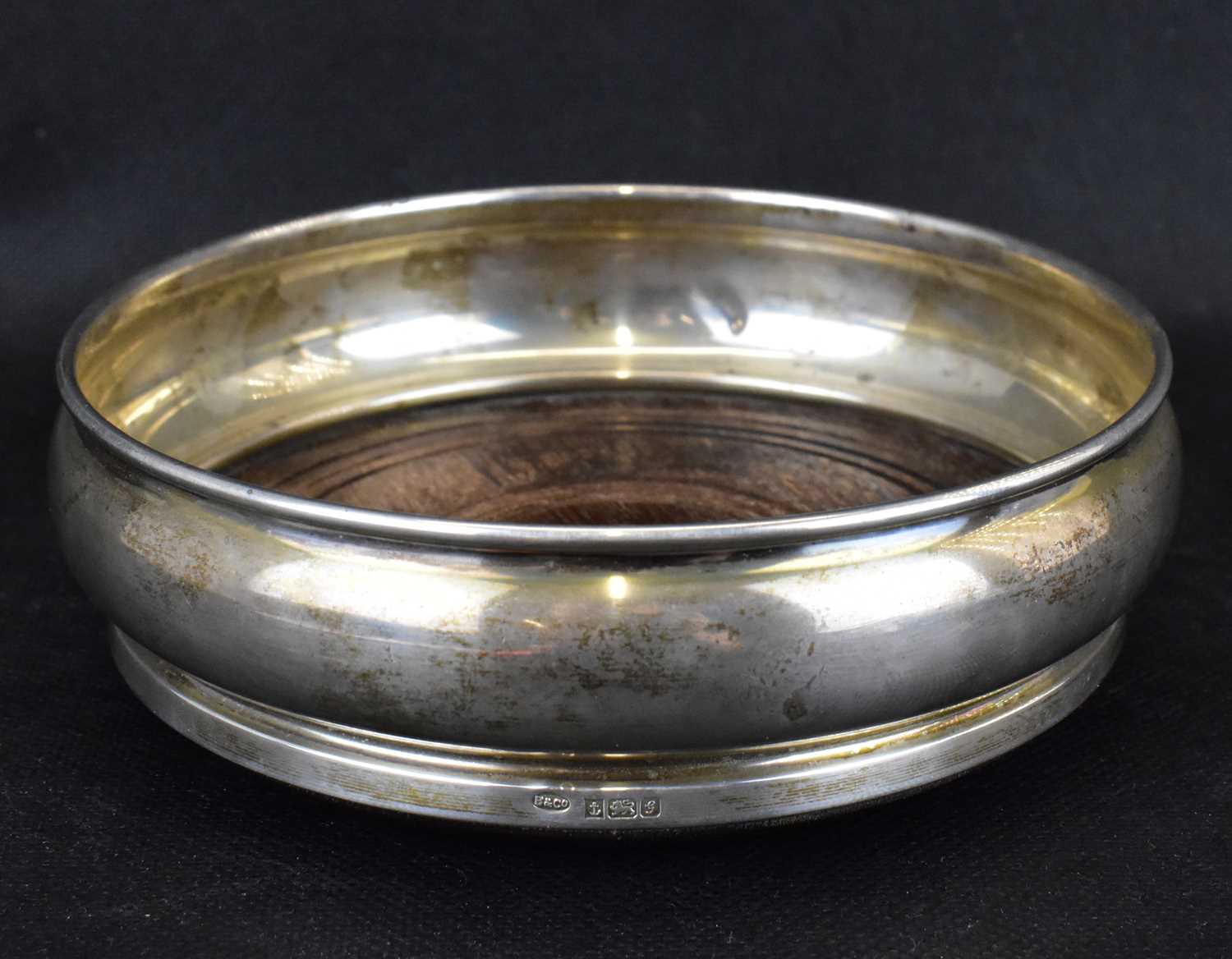 An Elizabeth II hallmarked silver wine coaster with circular wooden insert and green baize base, W I