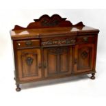An early 20th century walnut breakfront sideboard, the arched pediment back with carved floral