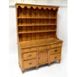 An early 20th century pine dresser, the boarded plate rack above frieze cushion drawers and panel