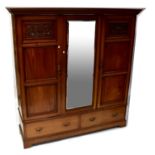 An Edwardian walnut triple wardrobe, the architectural-type pediment above bevelled glass central